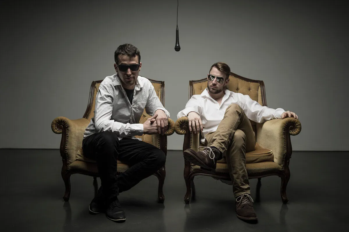 Tailgate Chamber: Nicolas and Ben standing side by side against a white wall